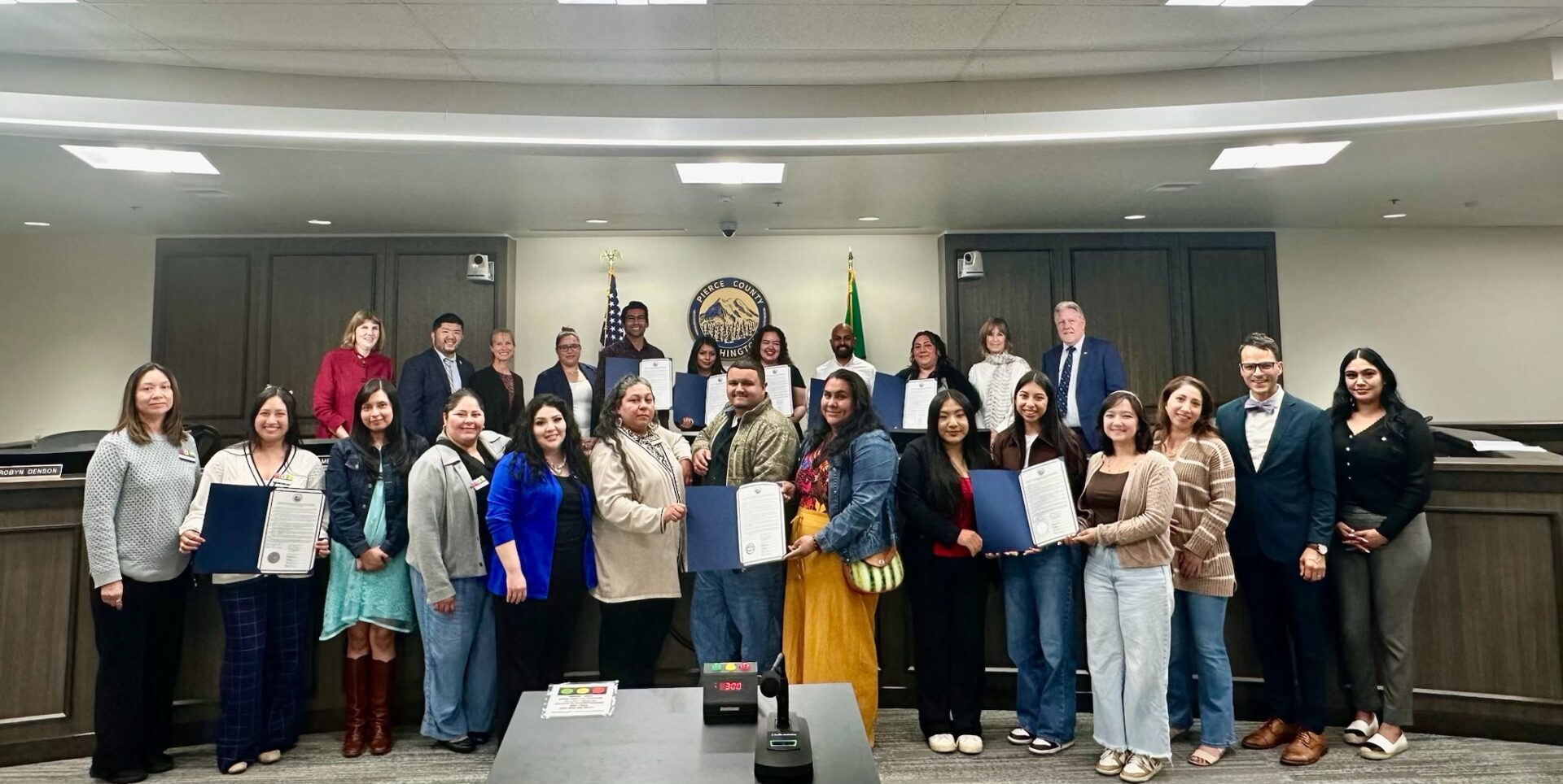 Representantes de la comunidad hispana y latina posan junto a funcionarios del Condado de Pierce con las proclamaciones por el Mes de la Herencia Hispana y Latina.