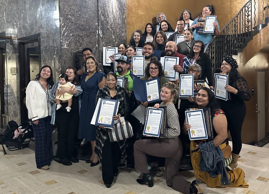 Integrantes de la comunidad posan en las escaleras con copias de la proclamación del Mes de la Herencia Hispana y Latina en Tacoma.