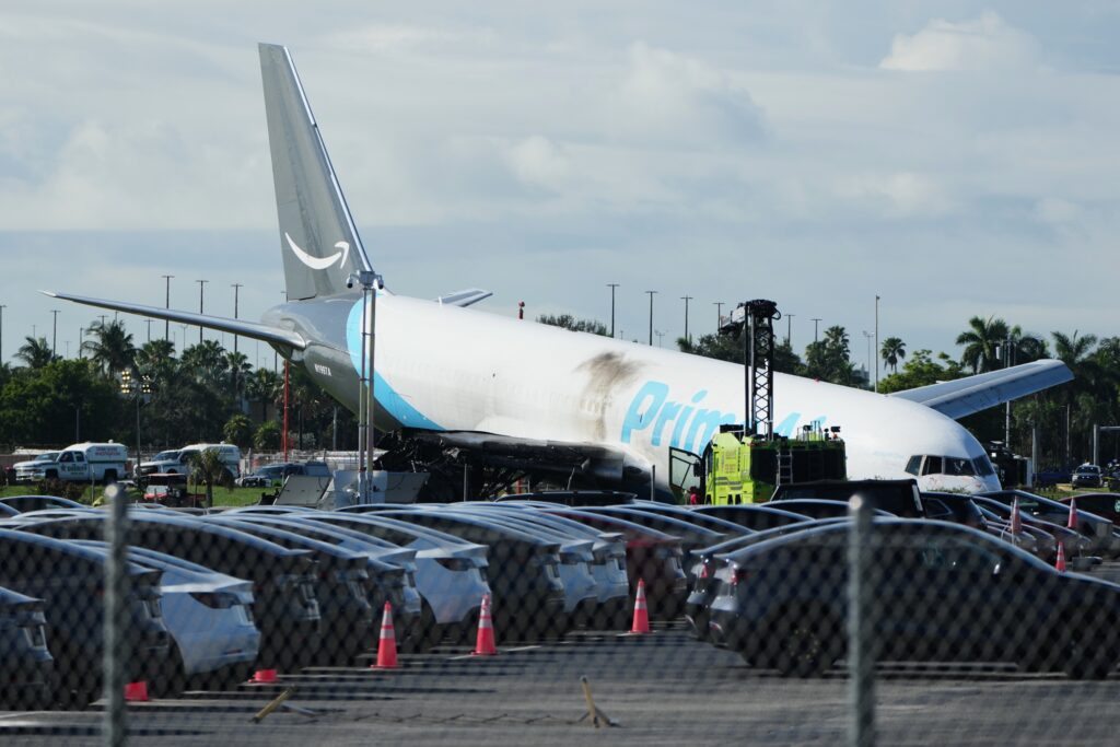 Avión de carga Prime Air de Amazon permanece fuera de la pista del Aeropuerto Internacional de Miami mientras equipos de emergencia trabajan en el lugar del accidente.