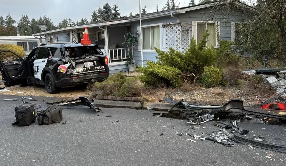 Vehículo de la Policía de Everett y restos de una colisión frente a una vivienda después de un incidente con un camión robado.