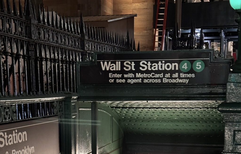 Entrada a la estación Wall Street del metro de Nueva York, con el letrero de las líneas 4 y 5 y las escaleras que conducen al andén.