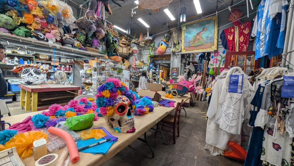 Taller de artesanías con calaveras decoradas, flores de papel de colores, máscaras y vestuarios tradicionales relacionados con el Día de Muertos.