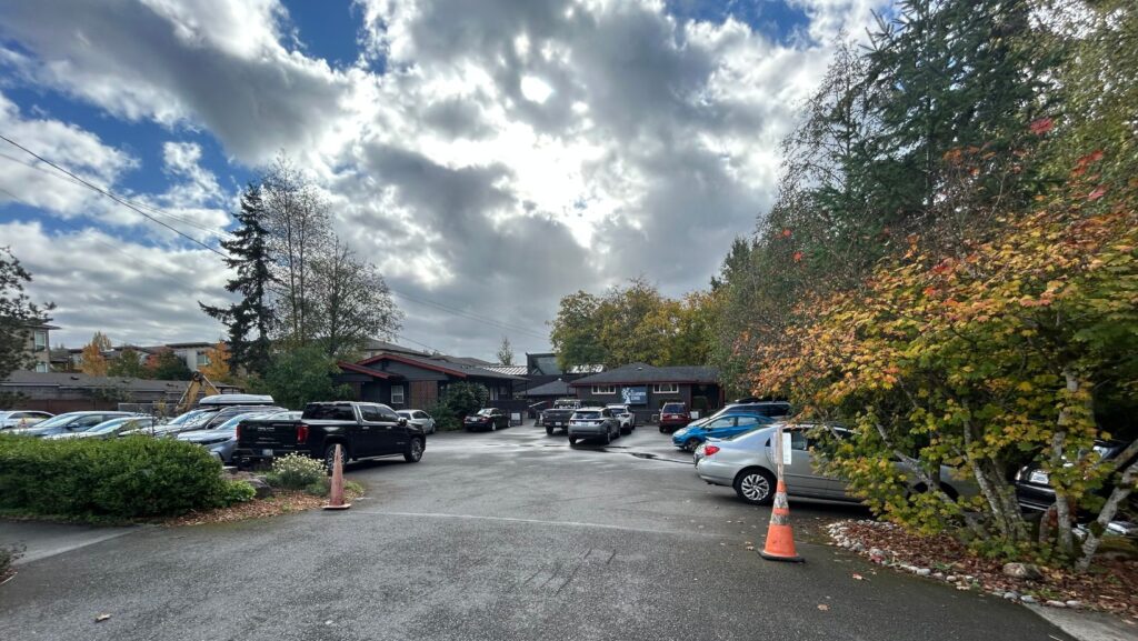 Vista del estacionamiento y los edificios de The Clearwater School, en Bothell, Washington, bajo un cielo parcialmente nublado.