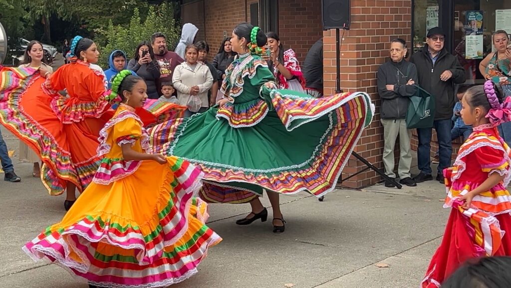 Bailarinas con coloridos vestidos tradicionales realizan una presentación folclórica frente al público durante la celebración del Mes de la Herencia Hispana en Lynnwood.