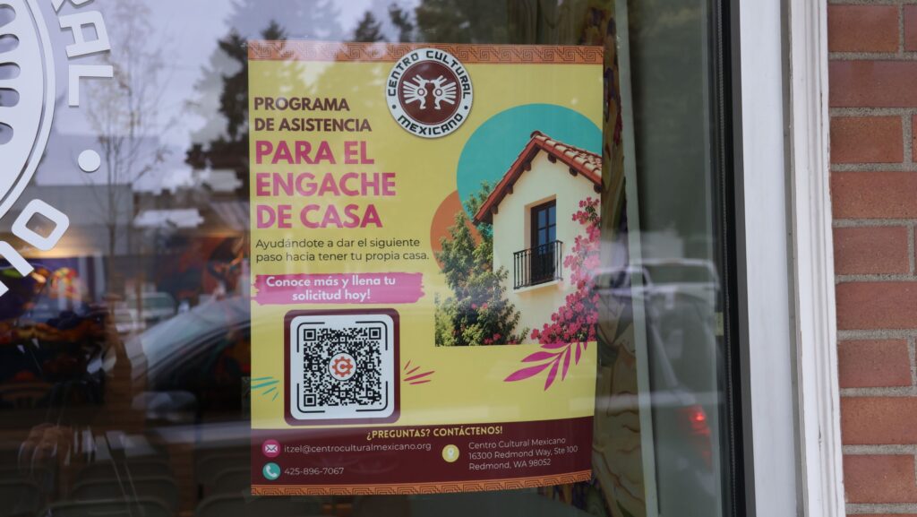Afiche del programa de asistencia para el enganche de vivienda colocado en una ventana del Centro Cultural Mexicano en Redmond.