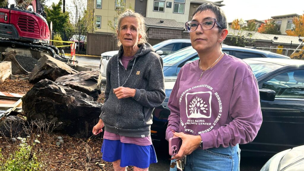 Stephany Sarantos, a la izquierda, y Karina Gasperín, a la derecha, posan frente a vehículos estacionados en las instalaciones de The Clearwater School, en Bothell.