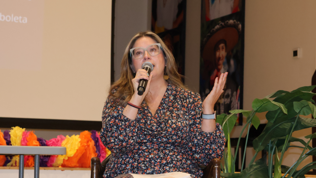 Maribel Pastor, gerente de Comunicaciones de Villa Comunitaria, habla por un micrófono durante un encuentro comunitario sobre las elecciones en South Park, Seattle.