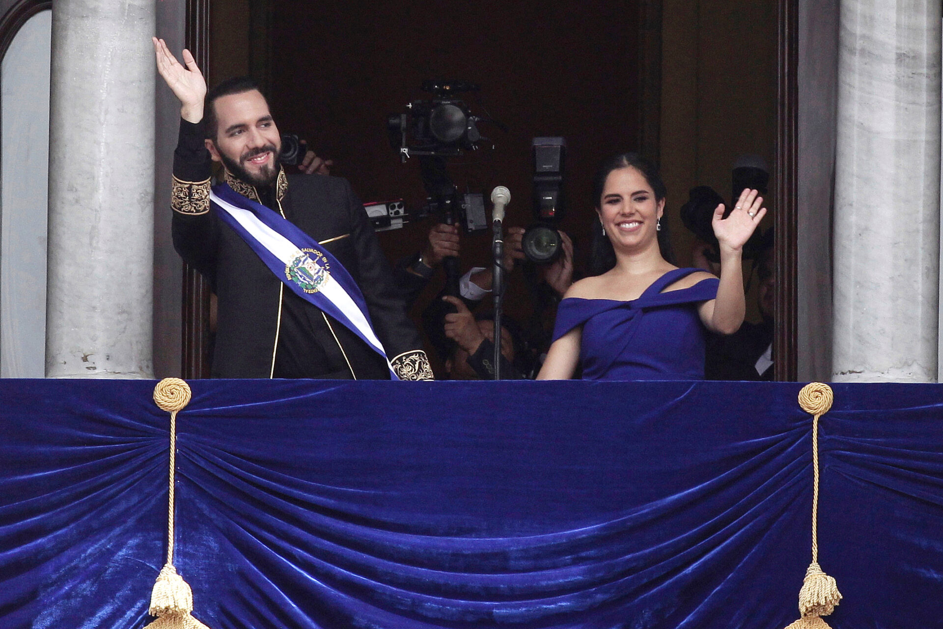 El presidente de El Salvador, Nayib Bukele, y su esposa, la primera dama Gabriela Rodríguez, saludan desde un balcón durante la ceremonia de investidura presidencial en San Salvador, el 1 de junio de 2024.