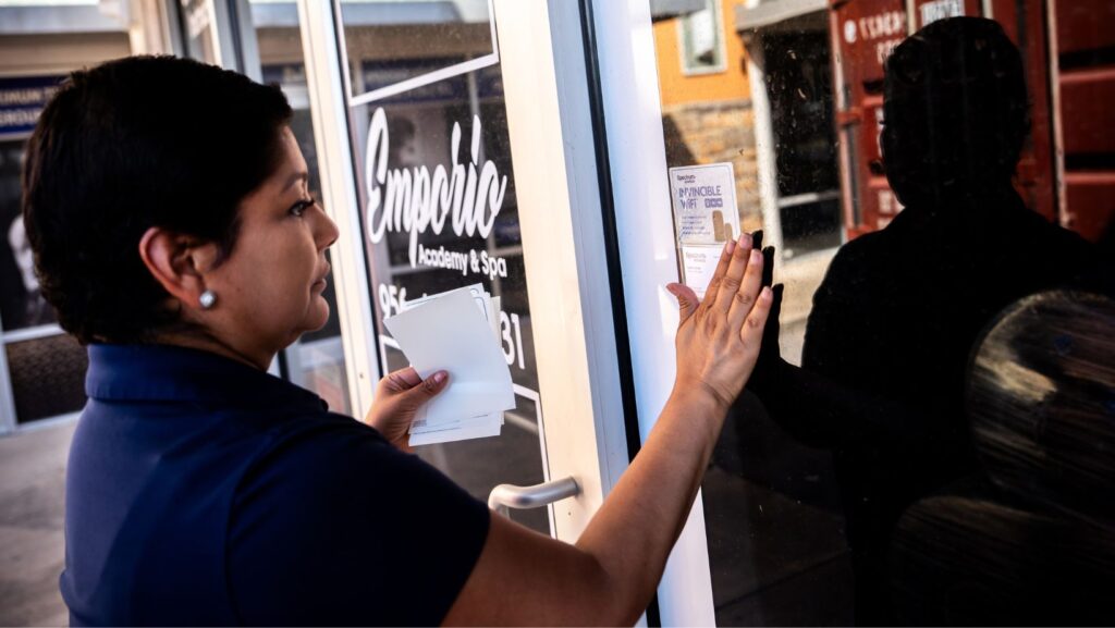 Cindy Banda pega un folleto publicitario de los servicios de Spectrum cerca de la puerta de Emporia Academy and Spa, el 14 de septiembre de 2026, en McAllen, Texas. (Foto AP/Julia Demaree Nikhinson)