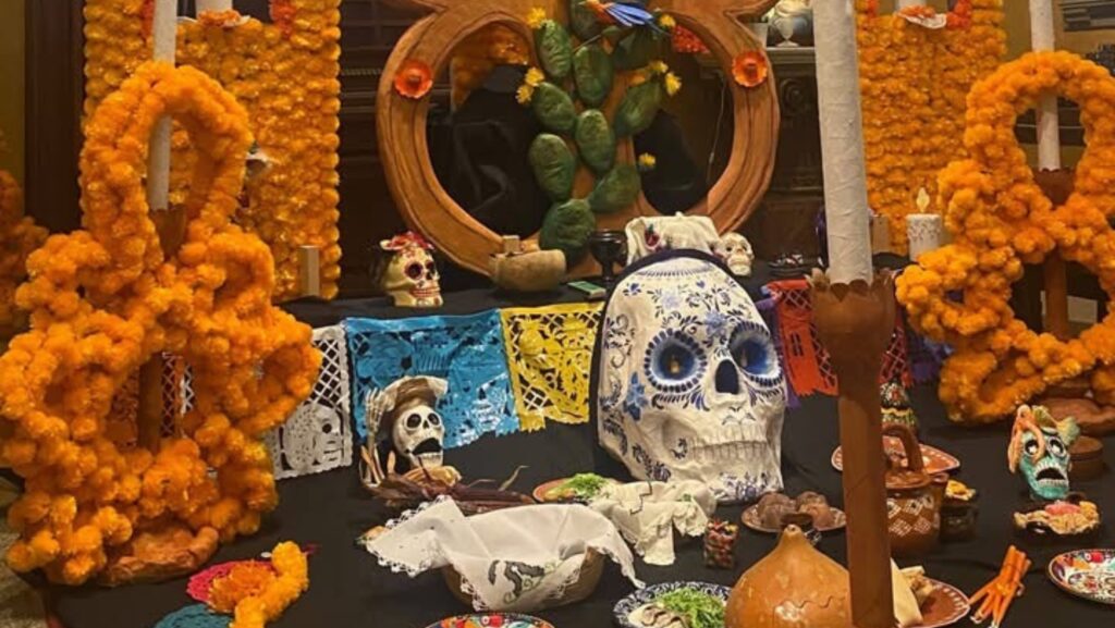 Detalle del altar de Día de Muertos en la Catedral Saint James de Seattle, con una gran calavera blanca decorada con motivos azules, flores de cempasúchil, velas, papel picado y figuras tradicionales mexicanas.