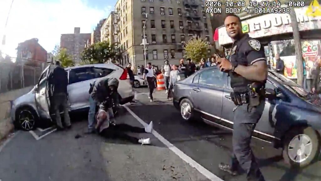 Imagen de la cámara corporal de un agente del Departamento de Policía de Nueva York. Personal de las fuerzas del orden atiende a un hombre dominicano que recibió disparos de agentes de inmigración el jueves 8 de octubre de 2026, mientras conducía su automóvil con un niño de 5 años a bordo. (NYPD vía AP)