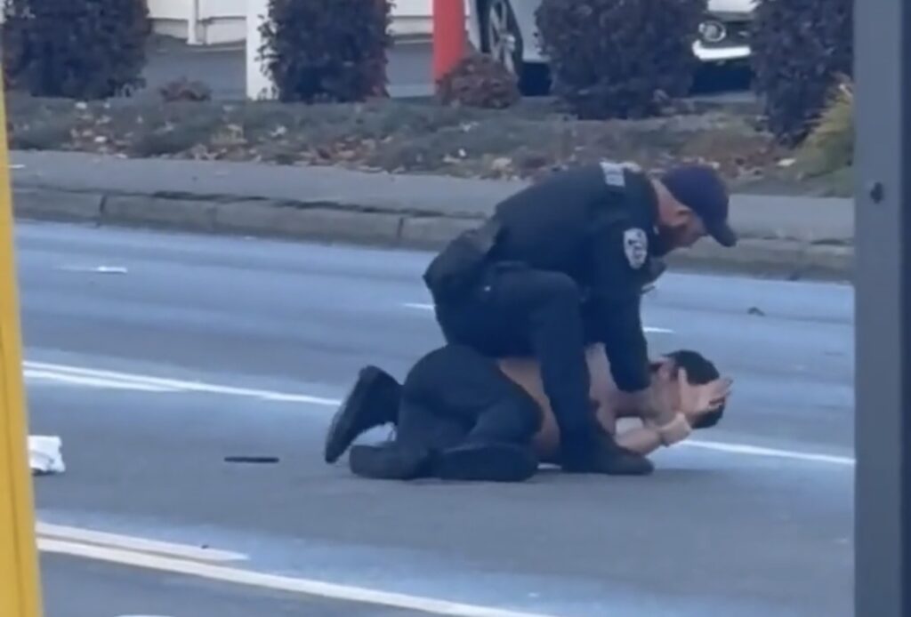Un agente de la Policía de Auburn permanece encima de Mauro Alberto Félix, quien está tendido en el pavimento con las manos cerca de la cabeza, durante una detención en Auburn, Washington.
