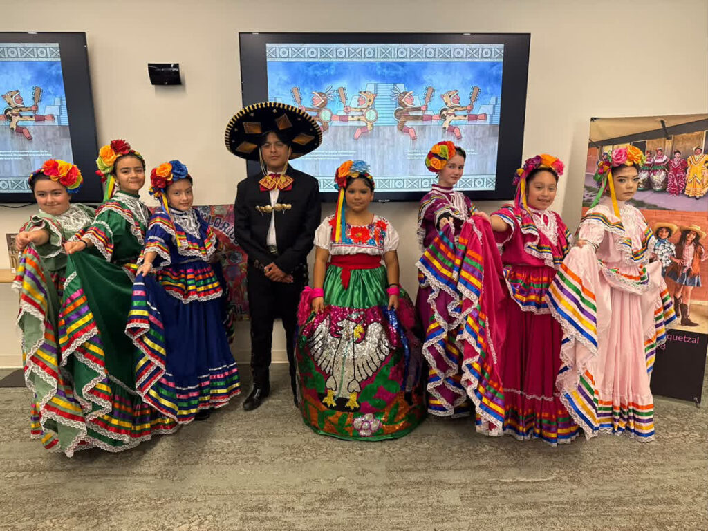 Integrantes juveniles del Ballet Folklórico Xochiquetzal posan con coloridos trajes tradicionales mexicanos durante una actividad cultural.